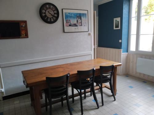 een eettafel met stoelen en een klok aan de muur bij gîte St Pierre in Melle