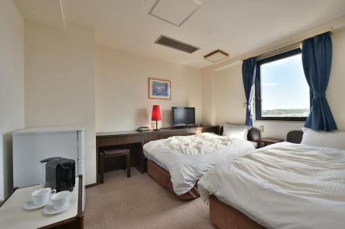 鈴鹿的住宿－Suzuka Royal Hotel，一间卧室设有两张床、一张桌子和一个窗口。
