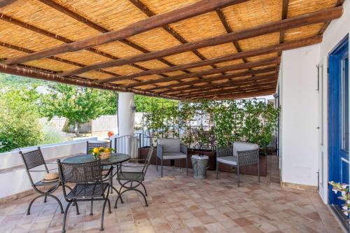 a patio with a wooden pergola and tables and chairs at Vico San Lorenzo - Camere a Salina in Malfa