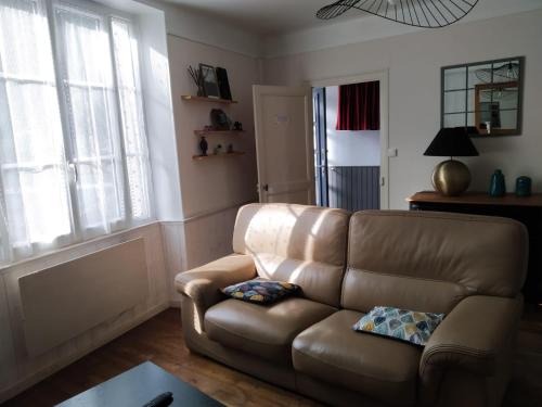 a brown leather couch in a living room with a window at gîte St Pierre in Melle