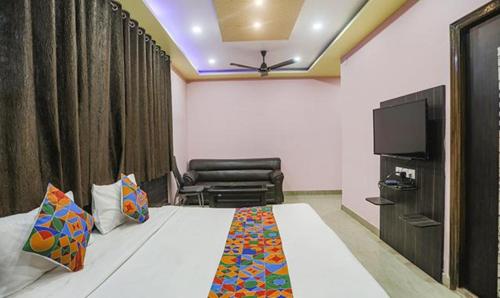 a room with a bed and a chair and a television at FabExpress Banarasi Kothi in Varanasi