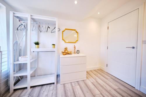 a white dressing room with a mirror and a white dresser at Pluxa Lemon Quartz - Wi-Fi, Workspace, Parking, in Sutton in Sutton