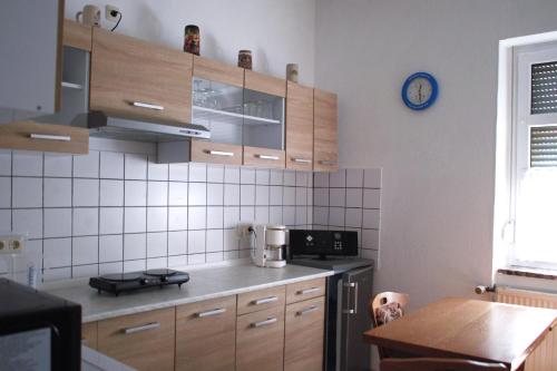 a kitchen with wooden cabinets and a table and a clock at Ferienwohnung Rose in Schöneck