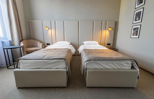 two beds in a small room with a chair at Regency Hotel in Chişinău