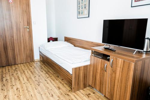 ein kleines Schlafzimmer mit einem Bett und einem Flachbild-TV in der Unterkunft Penzion Černý Sklep in Dobšice