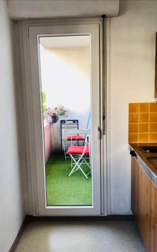 a door leading to a patio with a red chair at HAPPY STUDIO 35 ST Louis in Saint-Louis
