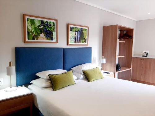 1 dormitorio con 1 cama blanca grande con almohadas verdes en De Zalze Lodge en Stellenbosch