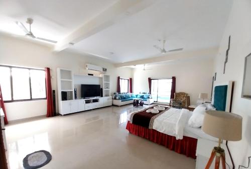 a large room with a bed and a television at Mango Valley Resort Ganpatipule in Ratnagiri