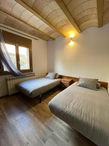 1 dormitorio con 2 camas y ventana en Casa de les Escoles, Espinalbet - ALBERGA, en Castellar del Riu