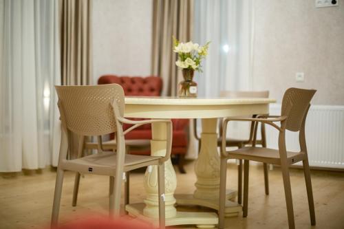 einen Esstisch mit Stühlen und eine Vase aus Blumen in der Unterkunft Moedani-Very Center Apartments in Kutaisi in Kutaissi