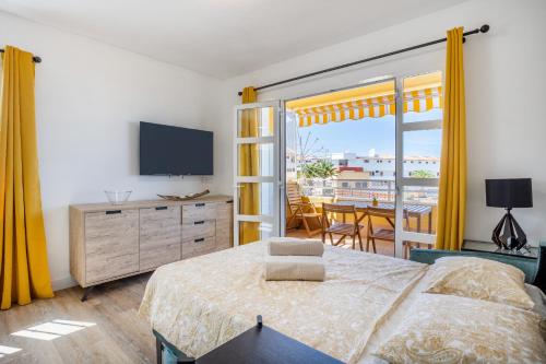 a bedroom with a bed and a tv and a balcony at Great Ocean View Torviscas Beach Home by LoveTenerife in Adeje