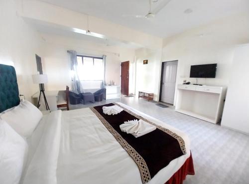 a large white room with a bed and a tv at Mango Valley Resort Ganpatipule in Ratnagiri