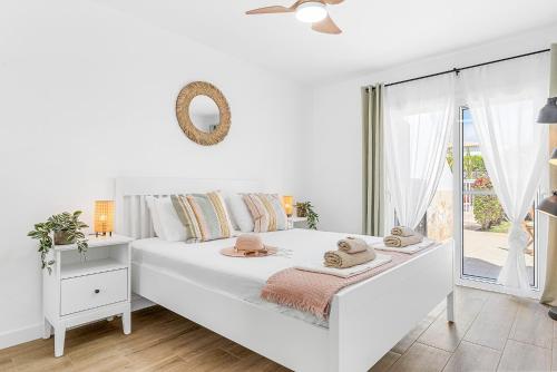 a white bedroom with a white bed and a window at Holiday Garden House in Golf del Sur in San Miguel de Abona