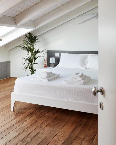CuggionoにあるB&B Funtaninの白いベッドとウッドフロアの白いベッドルームが備わります。