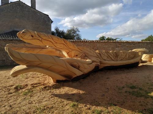a wooden bench shaped like a butterfly laying on the ground at gîte St Pierre in Melle