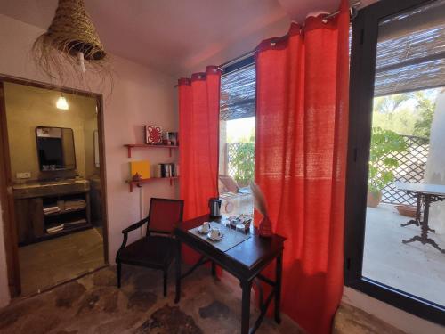 a room with red curtains and a table and a window at Finca Gomera - Agroturismo Hotel in Cala Pi