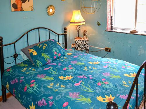 un letto con copriletto blu e fiori sopra di Dormys Cottage a Skegness