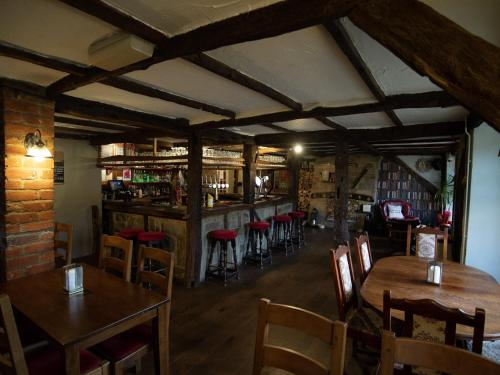 a restaurant with wooden tables and chairs and a bar at The Heath Inn in Leighton Buzzard