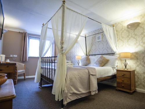 a bedroom with a canopy bed with a crib at The Heath Inn in Leighton Buzzard