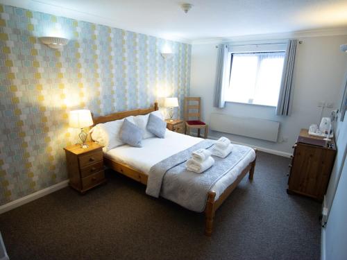a bedroom with a bed with two towels on it at The Heath Inn in Leighton Buzzard