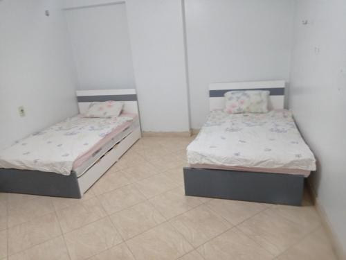 two beds in a room with white walls at الفرعون المصري in `Ezbet Bûgti
