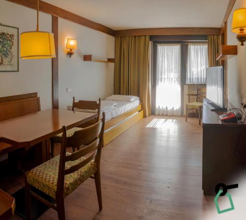 un soggiorno con letto e tavolo da pranzo di HOTIDAY Residence San Martino a San Martino di Castrozza