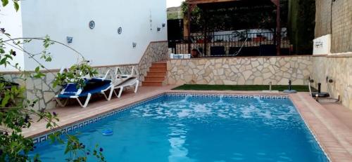 a swimming pool with two chairs next to a building at Casa Magnolia in Dúrcal