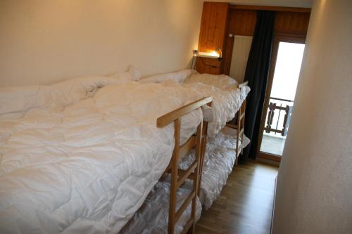 een slaapkamer met een wit bed en een houten vloer bij Greppons O 031 - MOUNTAIN apartment 10 pers in Veysonnaz