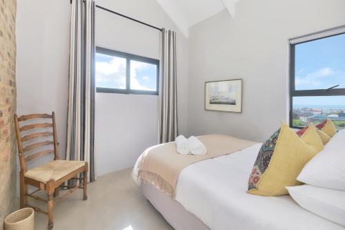 a bedroom with a bed and a chair and a window at Agulhas Seabreeze, tip of Africa in Agulhas