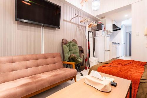 sala de estar con sofá, cama y TV en #803 Opening sale! Private rental Osaka city central Has the longest shopping street and you can enjoy the real Osaka, which has not yet become a tourist destination, en Osaka