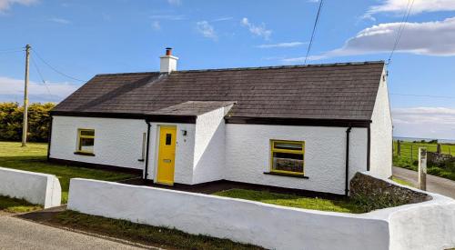 a small white house with a yellow door at Tyrella Cottage in Tyrella