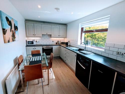 a kitchen with white cabinets and a table with chairs at Tyrella Cottage in Tyrella