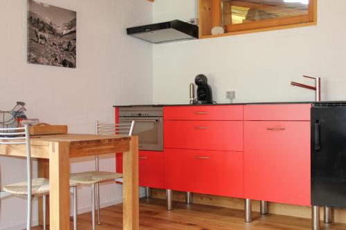 a kitchen with red cabinets and a wooden table at Hotel Ducan in Monstein