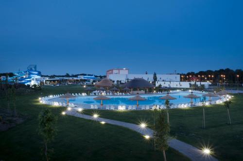 a large swimming pool with umbrellas at night at Mjus Resort & Thermal Park in Körmend