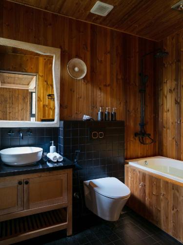 a bathroom with a sink and a toilet and a tub at Mơ Stay - Forest Resort in Da Lat