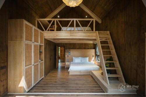 a bedroom with a bunk bed and a ladder at Mơ Stay - Forest Resort in Da Lat