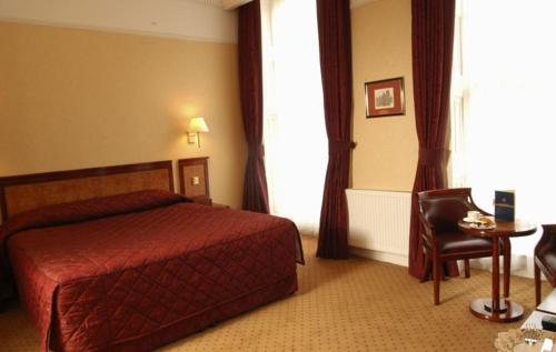 a hotel room with a red bed and a table at Grange Clarendon Hotel in London