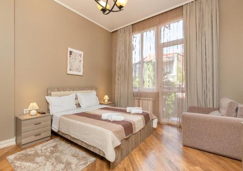 a bedroom with a bed and a couch and a window at HD Dream Apartment in Tbilisi City