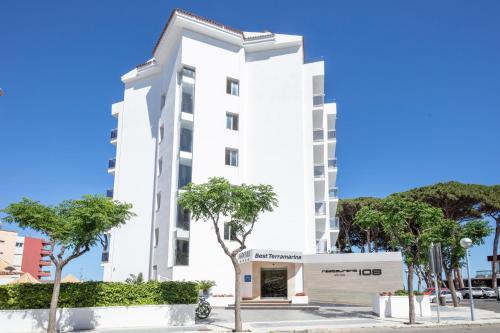 un bâtiment blanc avec des arbres devant lui dans l'établissement Hotel Best Terramarina, à La Pineda