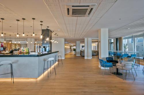 a lobby with a bar with chairs and tables at Hotel Best Terramarina in La Pineda
