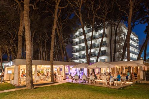 people sitting at tables in front of a building at night at Hotel Best Terramarina in La Pineda