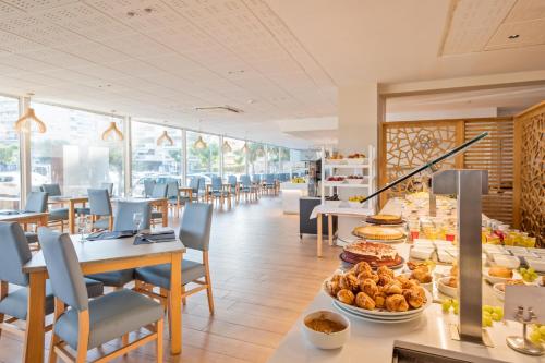 a restaurant with tables and chairs and food on display at Hotel Best Terramarina in La Pineda