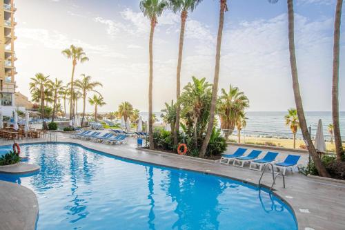 una piscina en la playa con palmeras y sillas en Hotel Best Benalmadena, en Benalmádena