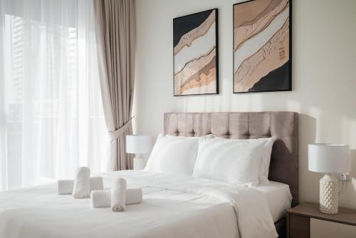 a white bedroom with a large bed with white pillows at LUXE 2BR at 1 RESIDENCES WASL NEAR METRO STATION in Dubai
