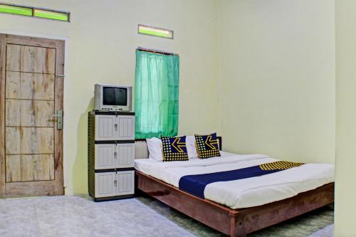 1 dormitorio con 1 cama, TV y puerta en SPOT ON 93089 Homestay Kamar Hijau Syariah, en Bandar Lampung