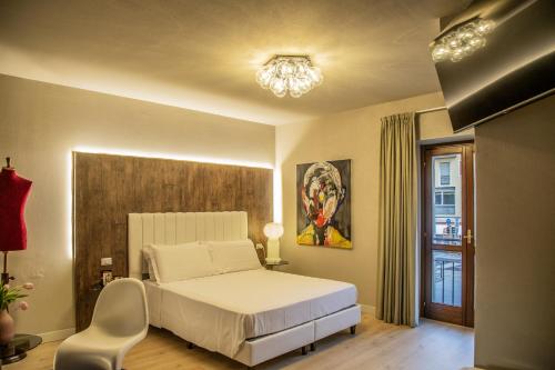 a bedroom with a bed and a chair and a chandelier at Hotel Battisti 31 in Brescia