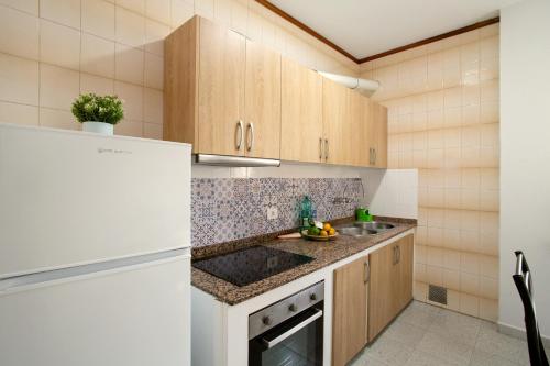 eine Küche mit Holzschränken und einem weißen Kühlschrank in der Unterkunft Apartamento Danoe 1 in Mogán