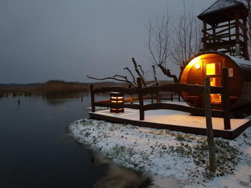 a tree house with lights in the water at night at Dolina Biebrzy - Chata Flisaka in Wroceń