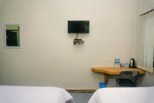 um quarto com duas camas e uma secretária com uma televisão na parede em GRAND KHALIFAH Guesthouse em Sumbawa Besar