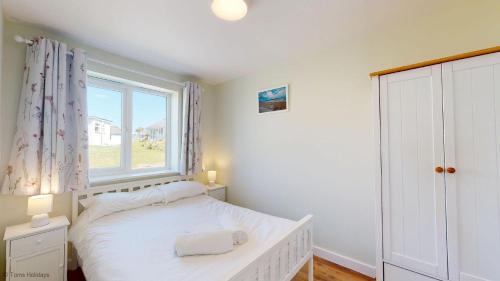 a bedroom with a white bed and a window at G07 Tweenbanx, Riviere Towans in Hayle